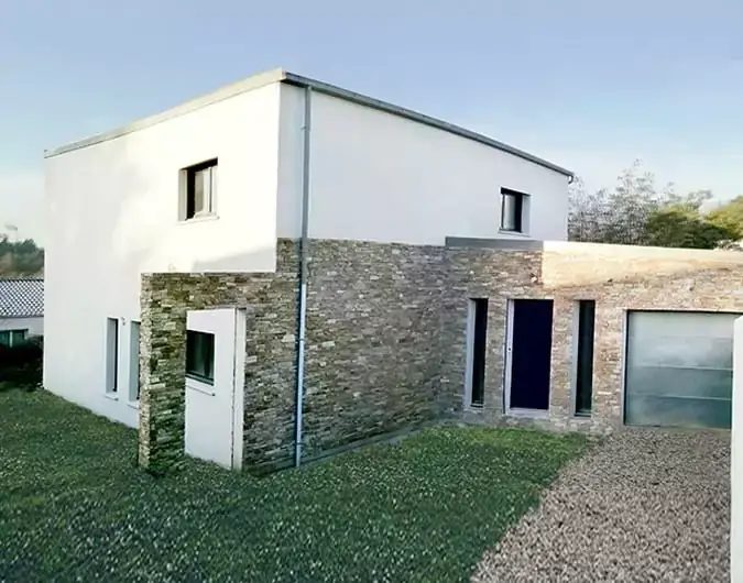 Maison contemporaine à deux niveaux avec façade en pierre et enduit blanc, dotée d'un garage, sur un terrain en gravier, sous un ciel clair.