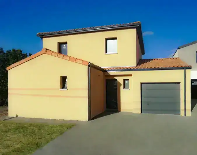 Maison à deux étages avec façade jaune, toit en tuiles et garage intégré, située sur un terrain en partie herbeux, sous un ciel bleu.