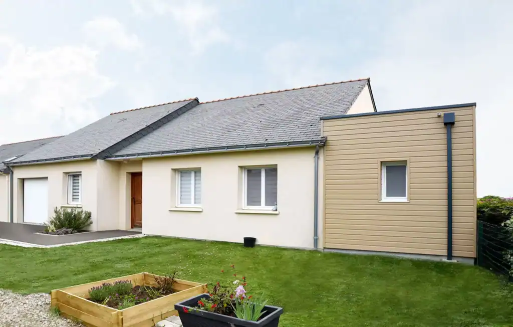 Une extension moderne et harmonieuse qui s’intègre parfaitement au style de la maison existante. Le bardage beige clair contraste élégamment avec la façade principale, créant un effet contemporain. Les finitions soignées, telles que les gouttières et les encadrements, renforcent l’aspect épuré. L’espace extérieur est optimisé avec une pelouse bien entretenue et un carré potager en bois, ajoutant une touche naturelle et fonctionnelle. Une réalisation esthétique qui apporte un nouvel espace de vie tout en valorisant l’architecture d’origine.
